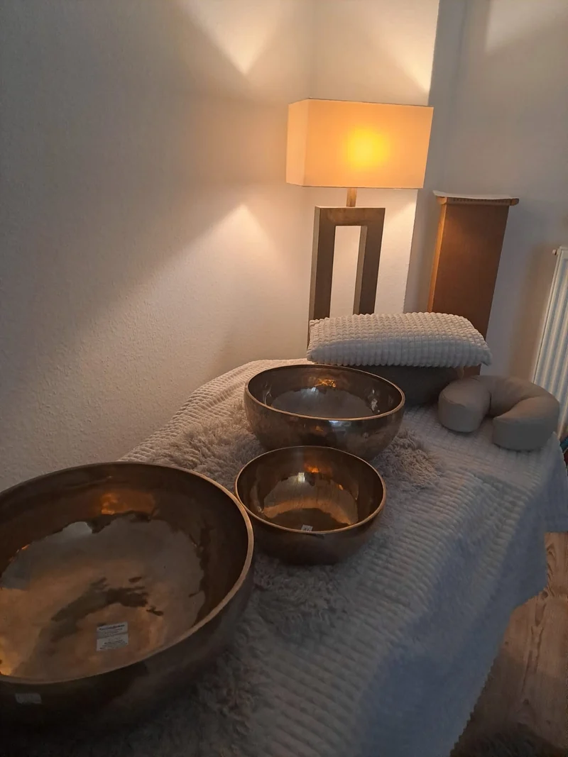 Klangschalen auf einer vorbereiteten Behandlungsliege im warmen Licht.