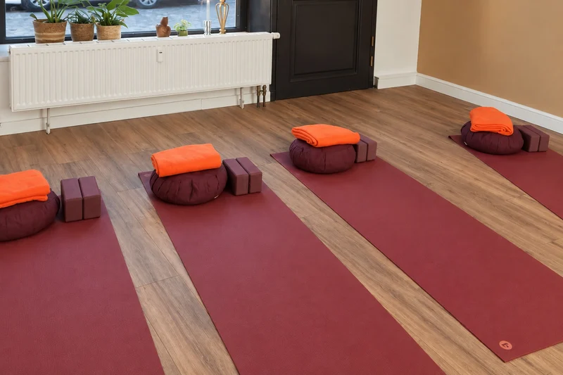 Vorbereitete Yogamatten mit Sitzkissen und orangefarbenen Decken im Studio.